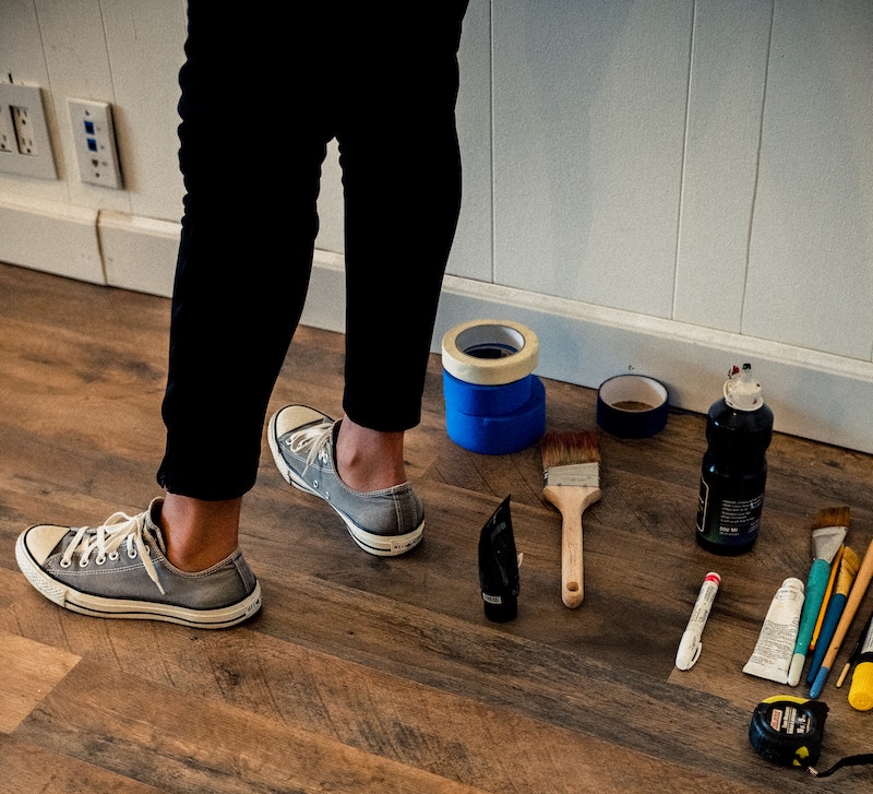 person's legs standing in a hallway next to painting materials person's legs standing in a hallway next to painting materials